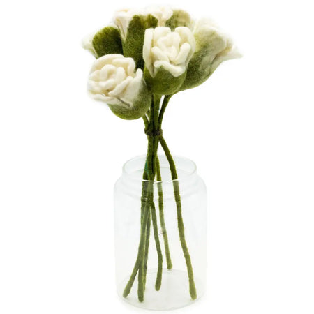 A bouquet of white roses made from felt with green accents arranged in a clear glass jar