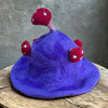 A whimsical purple felted mushroom hat with red polka dotted mushroom embellishments called dreamy purple haze