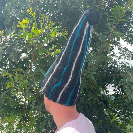 A black felted sauna wizard hat with bold teal and white stripes topped with a black pom-pom