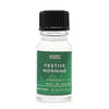 A clear glass bottle with black ribbed cap and green label reading ancient wisdom festive morning fragrance oil for christmas use