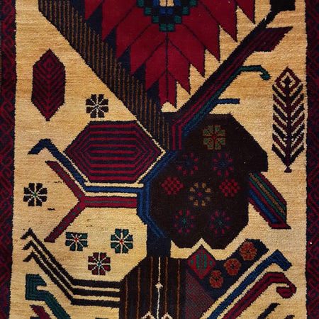 A handwoven afghan belouch rug with deep red navy blue black and cream geometric floral patterns on wool
