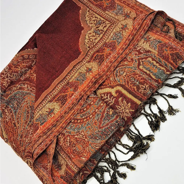 A terracotta and rust colored pashmina scarf with intricate paisley patterns dark brown fringe and maroon lining