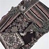 A fine woven pashmina shawl in muted black gray pink and white featuring textured floral and striped patchwork patterns
