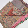 A soft pashmina shawl with a woven paisley pattern in muted earth tones and vibrant pink fringe