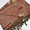 A richly patterned orange and beige pashmina shawl with intricate paisley design and fringed edges in earthy tones