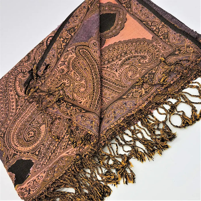 A soft peach and brown pashmina scarf with paisley patterns and black detailing with fringed edges