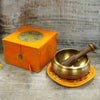 Golden five buddha singing bowl with dark wood mallet inside on an ornate orange saucer, 10cm buddha singing bowl set