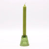 A slender olive green candle stands upright in a matching textured glass holder for candles in garden jade style