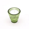 A green glass flip dinner candle tealight holder with vertical ridges and scalloped rim holding a white candle