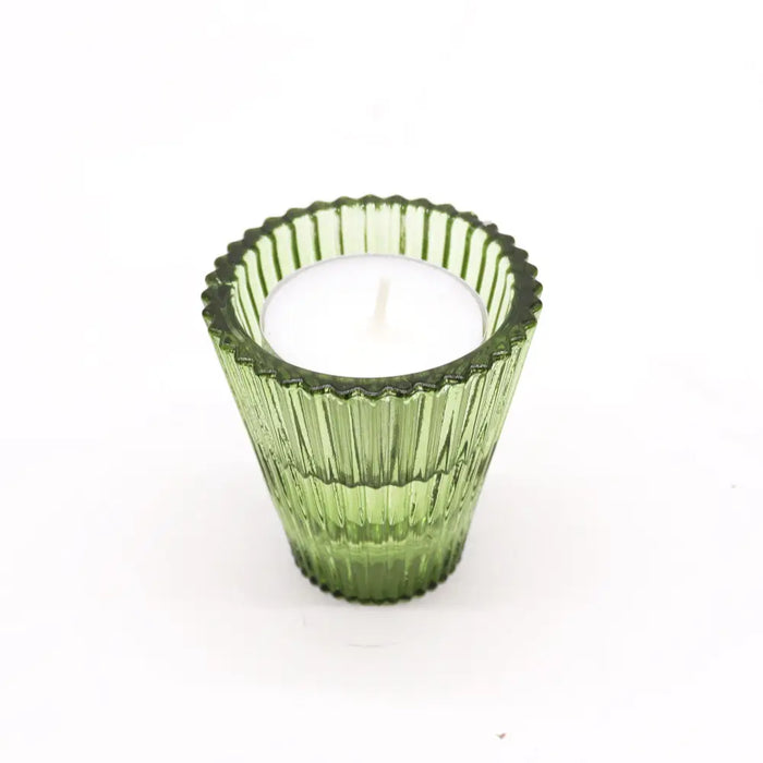 A green glass flip dinner candle tealight holder with vertical ridges and scalloped rim holding a white candle