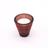 A deep red glass flip dinner candle holder with vertical ridges holds a white tealight candle for candles use