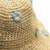 Beige floppy straw sun hat with light blue embroidered flowers and yellow centers made of woven straw material