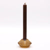 A tall slender brown candle in a textured antique amber glass flower flip dinner candle holder for candles