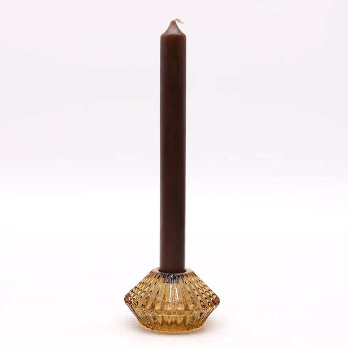 A tall slender brown candle in a textured antique amber glass flower flip dinner candle holder for candles