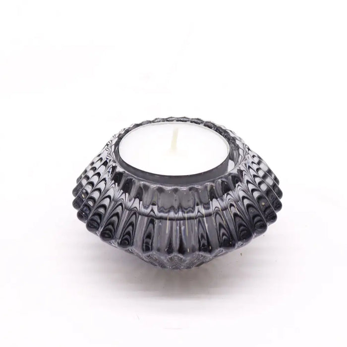 A dark gray glass flower flip dinner candle holder with a textured pattern and white tea light candle inside