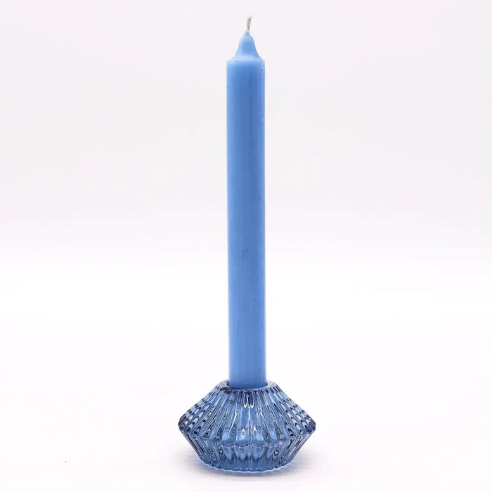 A solid blue flower flip dinner candle stands in a matching translucent glass tealight holder with a diamond base