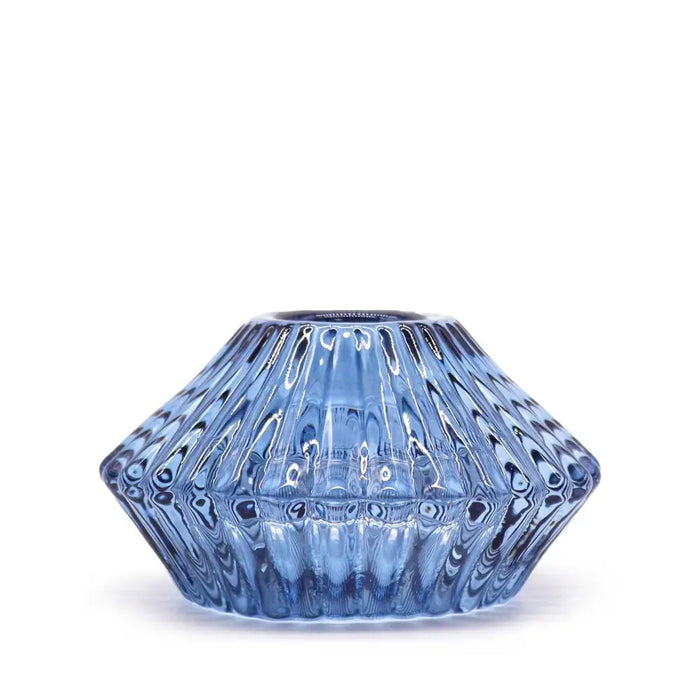 A translucent blue glass flower flip dinner candle holder with a faceted design and subtle internal swirls for candles
