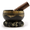 Black tibetan life singing bowl with gold geometric and feather engravings on a matching ring pillow singing bowl set