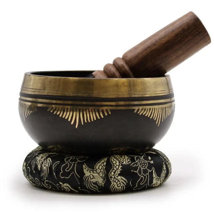 Black tibetan life singing bowl with gold geometric and feather engravings on a matching ring pillow singing bowl set