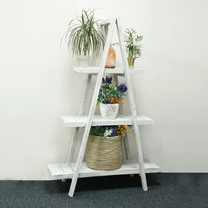 White distressed albesia wood folding a frame ladder shelf with four tiers holding plants and decor in whitewash finish