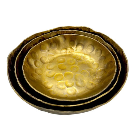 Set of three nested forged antique finished brass bowls with hammered textured surfaces and warm golden color