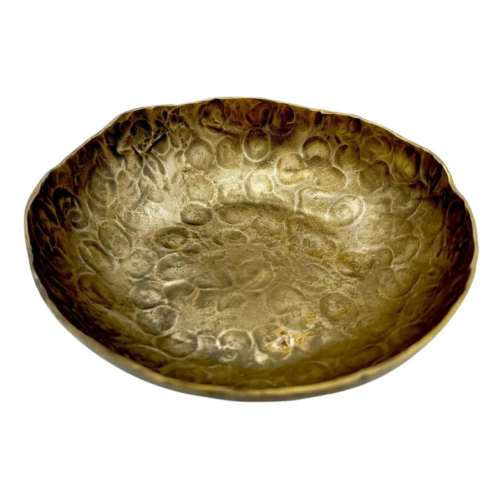 A hammered brass bowl with a textured golden surface and irregular rim in a forged antique finished style