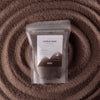 A clear pouch of millionaire gold candle sand in brown with minimalist white and brown ancient wisdom label 300g