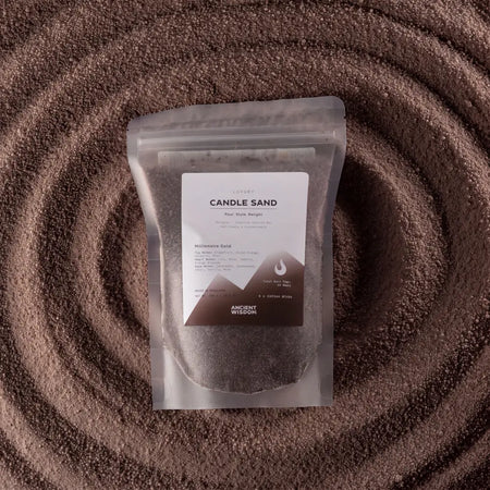 A clear pouch of millionaire gold candle sand in brown with minimalist white and brown ancient wisdom label 300g