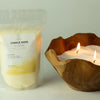 A rustic wooden bowl filled with white candle sand and two lit regent polo fragranced cream candles