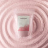 A pink translucent pouch of dusty rose candle sand by maison de boyer with a white and pink label reading candle sand