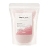A clear pouch of pink dusty rose candle sand with a white and pink label from ancient wisdom for roses candle sand