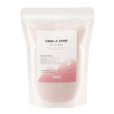 A clear pouch of pink dusty rose candle sand with a white and pink label from ancient wisdom for roses candle sand