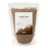 A clear pouch of fine dark brown fragranced mocha candle sand labeled crimson crystal candle by ancient wisdom 300g