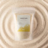 A clear resealable pouch of blush bloom candle sand labeled ancient wisdom fragranced warm honey 300g
