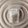 A clear resealable pouch with luxury white candle sand labeled starlight elixir by ancient wisdom 300g