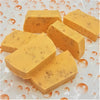 Six rectangular bars of golden yellow fruity handmade soap speckled with dried herbs in various fragrances
