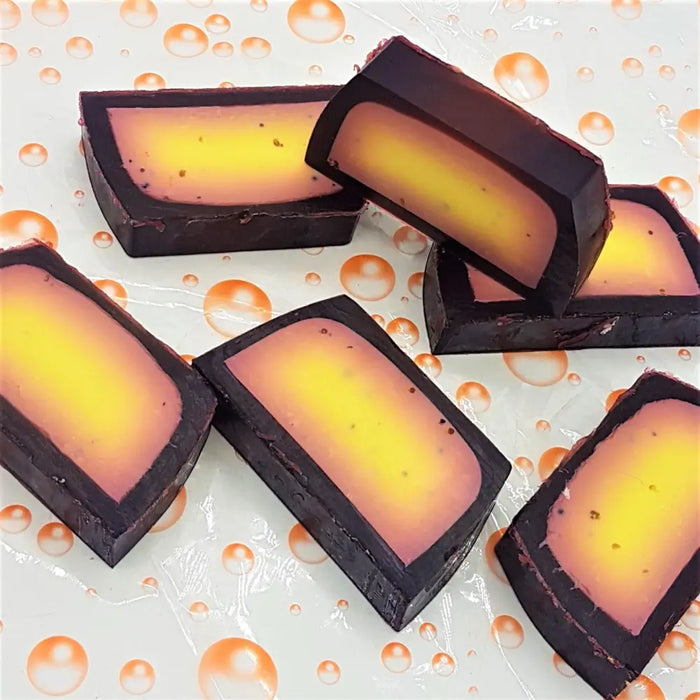 Rectangular fruity handmade soap slices with dark outer layer and yellow to orange gradient inner core in various fragrances