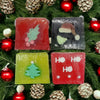 Four colorful handmade soap slices in red green and black with christmas themes like holly santa hat and tree designs