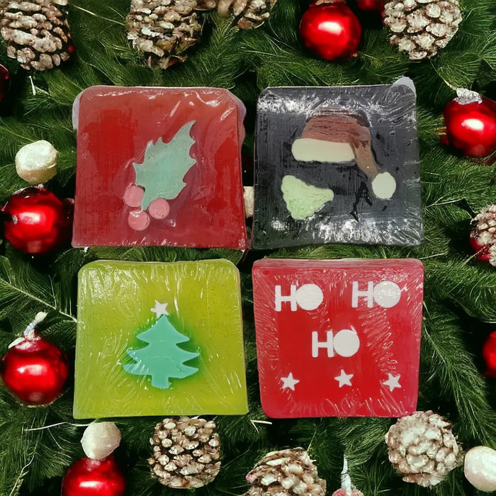 Four colorful handmade soap slices in red green and black with christmas themes like holly santa hat and tree designs