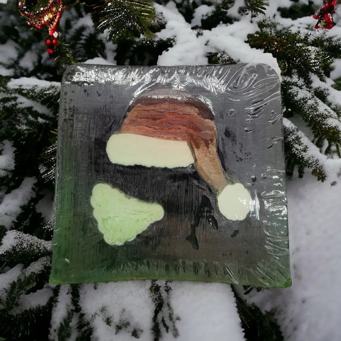 A square translucent green and gray handmade soap slice with a santa hat design and christmas themes