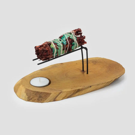 A gamal wood palo santo heater with a rustic wooden base and black metal stand holding a sage smudge stick wrapped in twine