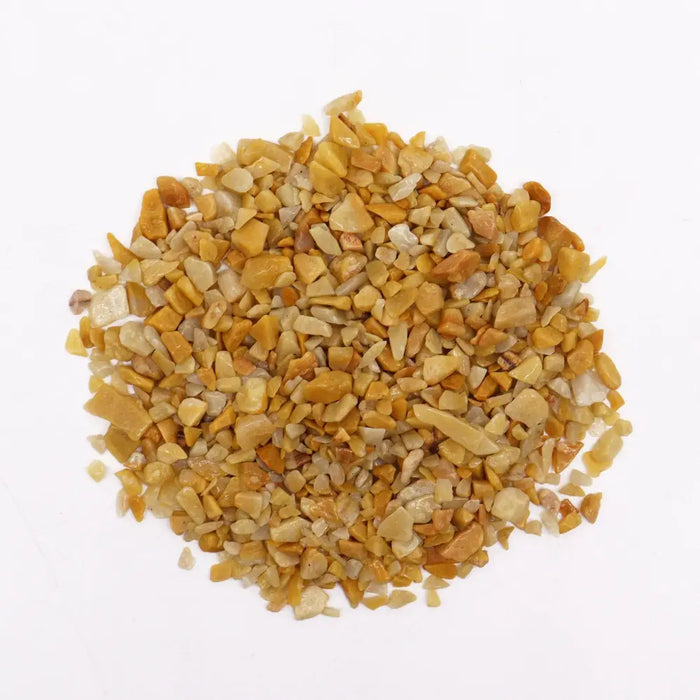 A pile of golden quartz chips in yellow and beige with a smooth polished texture for gemstone use