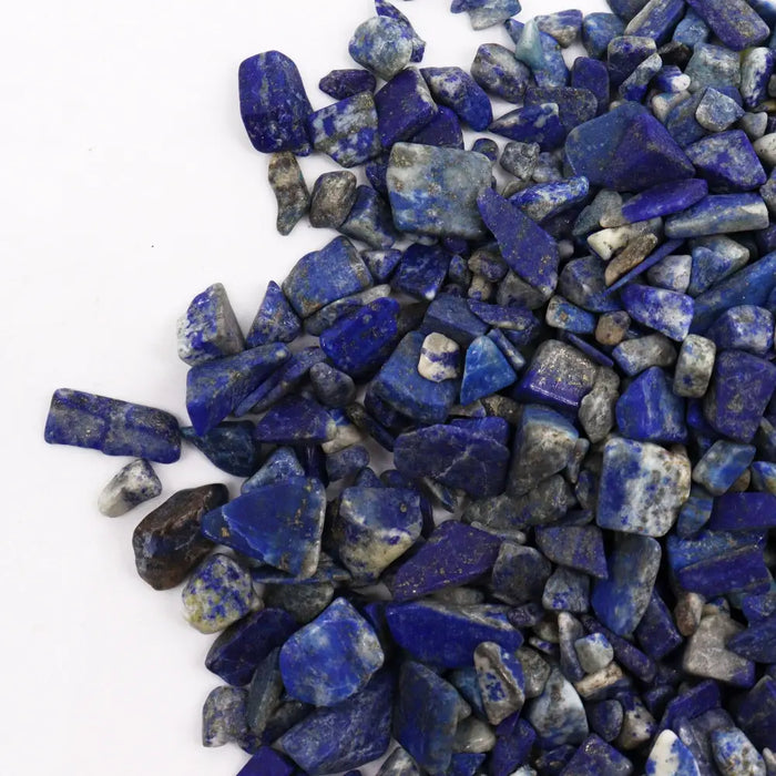 A pile of natural blue lapis lazuli gemstone chips showing deep royal and lighter azure hues with white veining