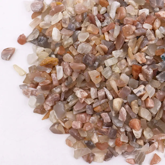 A pile of smooth rounded gemstone chips in earthy pale pink white and gray tones made from moonstone material