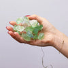 A delicate string of translucent green crystal jade beads with natural facets and thin wire wrapping for enchantment lights