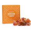 Orange jade gemstone enchantment lights with irregular translucent amber stones glowing warmly in a string setting