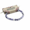 A delicate stretchy gemstone manifestation bracelet made of smooth round amethyst beads in purple and gray shades