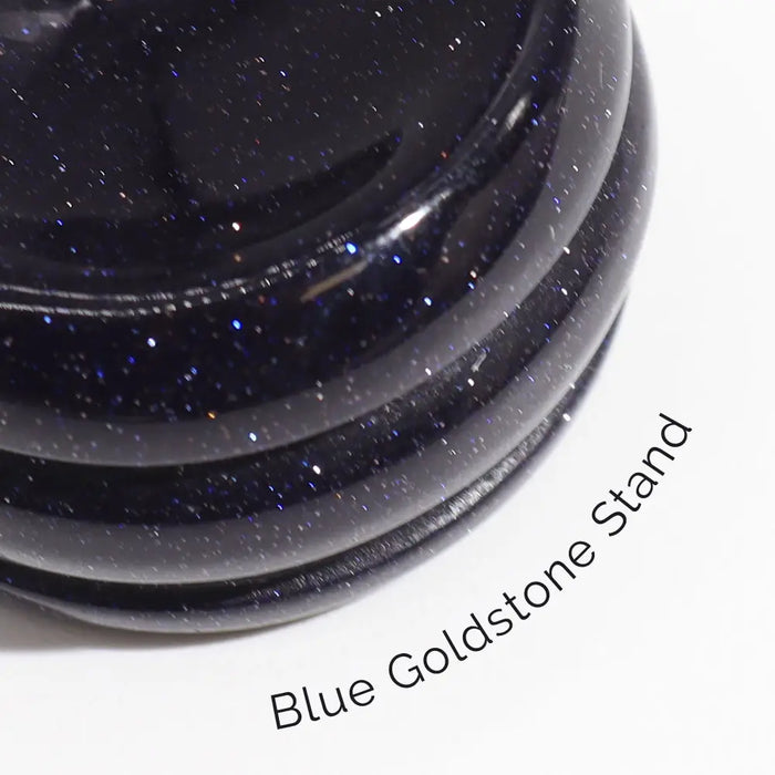 A gemstone planet red jasper mars on a sleek dark blue goldstone stand with glossy finish and sparkling particles