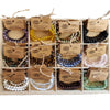 A collection of colorful gemstone power bracelets in purple yellow green black blue white and pink with mood stone labels