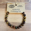 A tiger eye gemstone bracelet with polished round beads showing golden brown and dark brown stripes for mood balance